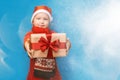 Little baby boy wear santa suit smile and show gift box with red bow on blue background. selected focus. christmas time Royalty Free Stock Photo