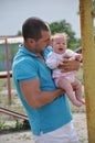 Little baby child kid crying on the hands of the young father outdoor in summer