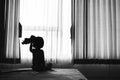 baby child sitting on bed playing with the doll in the dark room with light throught curtain