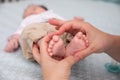 Little baby close-up legs and heart from fingers hold by mom`s palm.