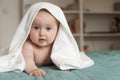 Little baby smiling. Cute baby lying on her tummy over a white towel