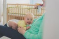 Little baby daughter lies on the lap of a young mother sitting on the couch