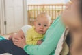 Little baby daughter lies on the lap of a young mother sitting on the couch