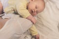 Little baby daughter lies on the lap of a young mother sitting on the couch