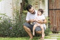 Little baby daughter sitting on her father scoop while rest in the garden at home. Handsome single dad holding and Royalty Free Stock Photo