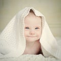 Little baby with Down syndrome hid under blanket and smiles slyly Royalty Free Stock Photo