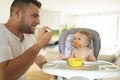 A Little baby eating her dinner and making a mess with dad on the side Royalty Free Stock Photo