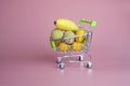 little baby fruits banana  lychee and kumquat in supermarket trolley on pink background Royalty Free Stock Photo