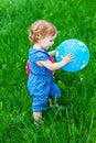 A little baby girl with a balloon in her hands on the green grass in a summer Park. Royalty Free Stock Photo