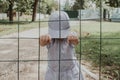 Little baby girl behind bars. The child holds onto the bars of the lattice. Royalty Free Stock Photo