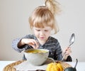 Little Girl Eating Pumpkin Cream-Soup at Home