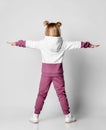 Little baby girl in a colorful sports suit stands with his back to the camera. Royalty Free Stock Photo