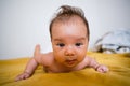Little baby girl crawling in bed at home with happy face on yellow sheet close up. Crawling is the first childhood milestone Royalty Free Stock Photo