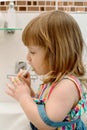 Little baby girl diligently brushing his teeth in the bathroom.Curly-haired girl laughs and shows clean teeth, child Royalty Free Stock Photo