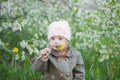 Little baby girl with Down syndrome in the mouth pulls dandelions