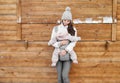 Little baby girl and her mother babywearing the ergo carrier in winter wooden background Royalty Free Stock Photo