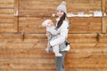 Little baby girl and her mother babywearing the ergo carrier in winter wooden background