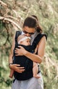 Little baby girl and her mother walking outside babywearing in the ergo carrier concept Royalty Free Stock Photo