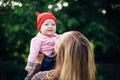 Little baby girl and her mother walking in the park. Red hat. Blue eyes. Royalty Free Stock Photo