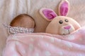 little baby girl hiding under her blanket with her easter bunny plush cuddly soft toy