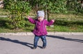 Little baby girl in jeans jacket and hat making learning to walk his first steps on the lawn in the green grass Royalty Free Stock Photo