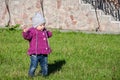 Little baby girl in jeans jacket and hat making learning to walk his first steps on the lawn in the green grass Royalty Free Stock Photo