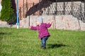 Little baby girl in jeans jacket and hat making learning to walk his first steps on the lawn in the green grass Royalty Free Stock Photo