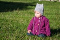 Little baby girl in jeans jacket and hat making learning to walk his first steps on the lawn in the green grass Royalty Free Stock Photo