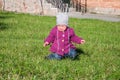 Little baby girl in jeans jacket and hat making learning to walk his first steps on the lawn in the green grass it has not very go Royalty Free Stock Photo