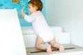 Little baby girl learning walking, standing and making first steps at home. Toddler climbing stairs and balancing. Happy Royalty Free Stock Photo