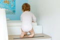 Little baby girl learning walking, standing and making first steps at home. Toddler climbing stairs and balancing. Happy Royalty Free Stock Photo