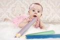 Little baby girl lying on the floor with big crayons Royalty Free Stock Photo