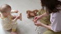 Little baby girl and mommy playing at home sitting on floor. Mother and daughter laughing having fun together