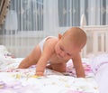 Little baby girl in a nappy crawling on a bed.