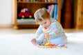 Little baby girl playing with educational wooden music toys at home or nursery. Toddler child with colorful wooden Royalty Free Stock Photo