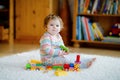 little baby girl playing with educational wooden toys at home or nursery. Toddler with colorful train. Child having fun Royalty Free Stock Photo