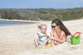 Little baby girl playing sand toys with her mother at the beach Royalty Free Stock Photo