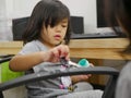 Little baby girl playing topical ointment - using a key to scoop it out and paint it on daddy`s office chair Royalty Free Stock Photo