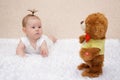 Little baby girl playing with a toy teddy bear