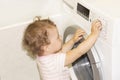 Little baby girl presses buttons on the washing machine