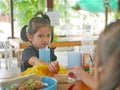 Little baby girl reaching her hand out for the same piece of deep fried wantan as taken by her younger sister - sisters / siblings