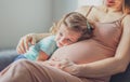 Little baby girl relaxing on mom`s pregnant belly - Pregnant mother with a toddler - Family concept Royalty Free Stock Photo