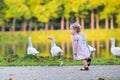 Little baby girl at river shore chasing wild geese Royalty Free Stock Photo