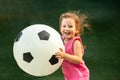 Little baby girl runs with a huge soccer ball. Royalty Free Stock Photo