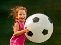 Little baby girl runs with a huge soccer ball. The girl rejoices and smiles. Royalty Free Stock Photo