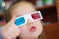 Little baby girl showing super in 3D anaglyph cinema glasses for stereo image system with polarization. 3D goggles with red and bl Royalty Free Stock Photo