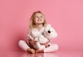 Little baby girl sits on the floor with white teddy bear and smiles happily Royalty Free Stock Photo