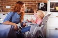 Little baby girl sits in high chair and feeding with spoon her beautiful mother Royalty Free Stock Photo