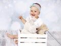 Little baby girl sitting on the floor with box of plush toys Royalty Free Stock Photo