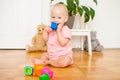 Little baby girl sitting on the floor, crawling and playing with brightly colored educational toys